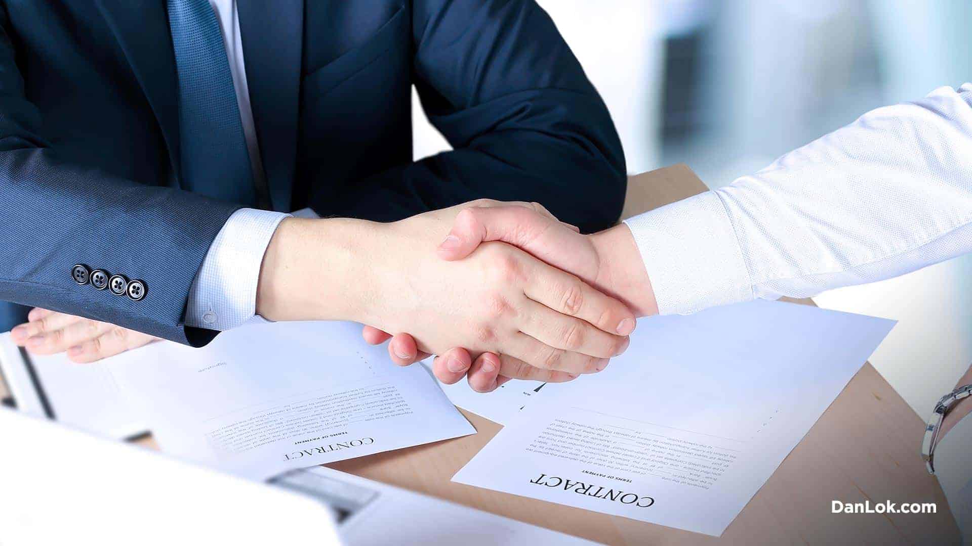 2 people shaking hands in front of a contract